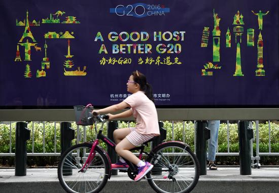 8月27日，在杭州市西湖南山路，一个小朋友骑车从G20宣传画前经过。 新华社记者 鞠焕宗 摄.jpg