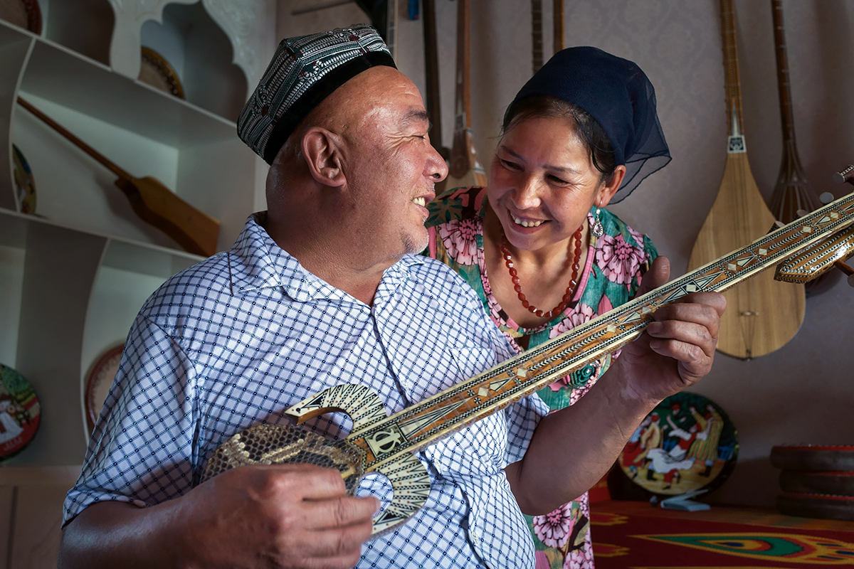 7-13  在丽水市援建的新和县天籁加依村，乐器制作匠艾依提·依明为妻子弹奏自己制作的乐器.jpg